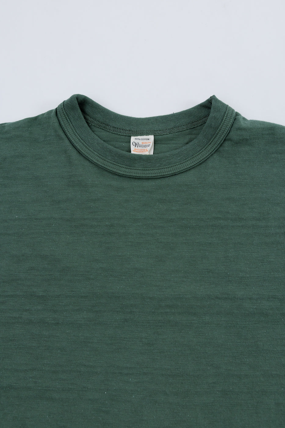 Close-up of front upper section, collar, and fabric texture of green slubby cotton t-shirt.