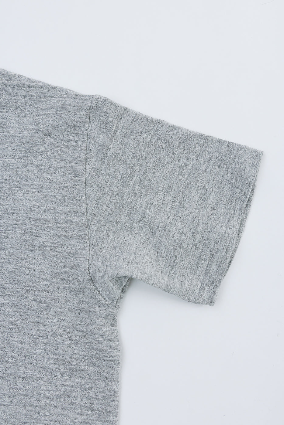 Close-up of heather grey cotton t-shirt showing left sleeve and fabric texture, front view