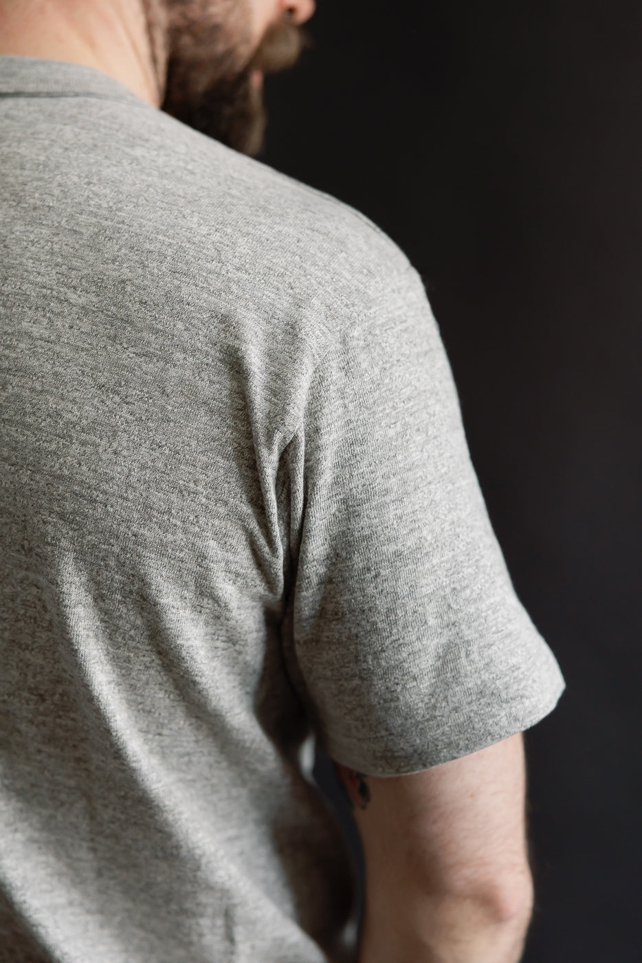 Close-up of back shoulder detail on heather grey slubby cotton T-shirt, modeled by male, 5'9