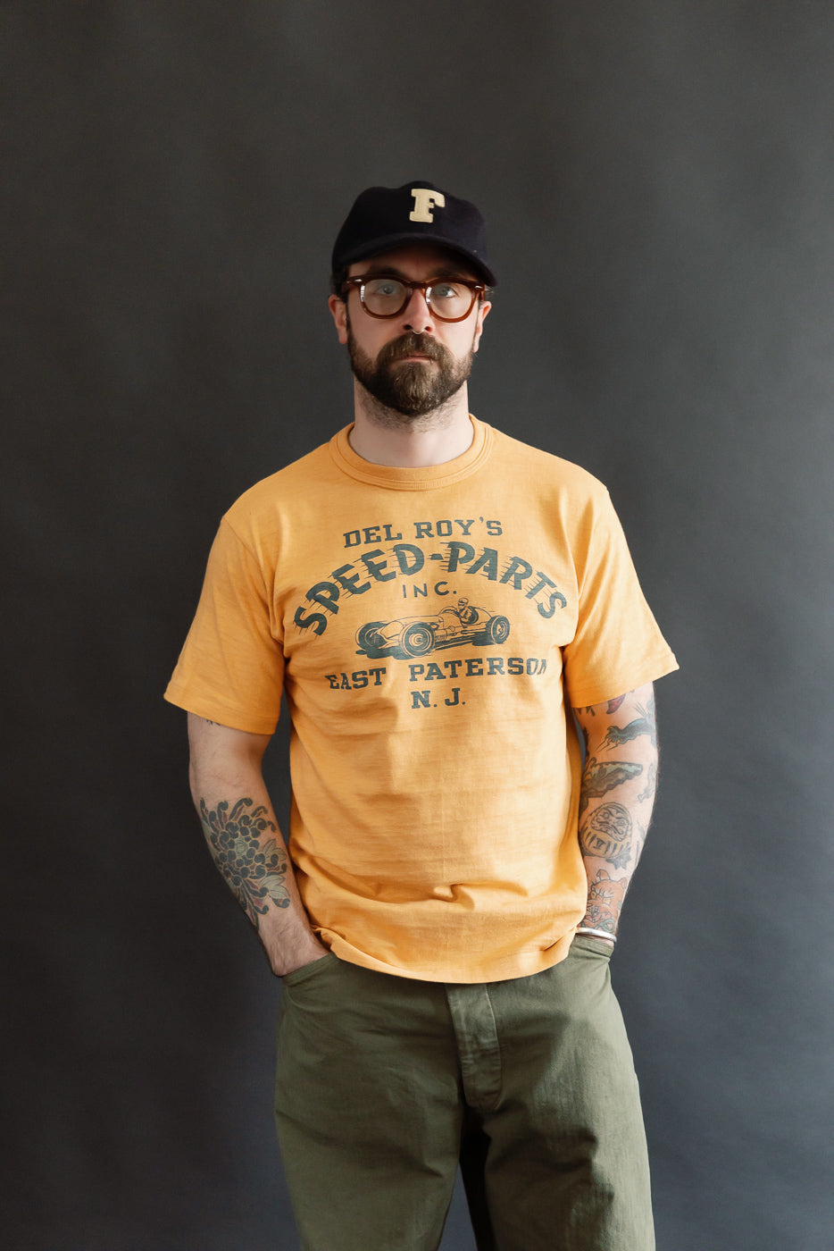 Male model 5'9 165lbs athletic build wearing orange Warehouse & Co. slubby cotton t-shirt, front view, vintage speed parts graphic.