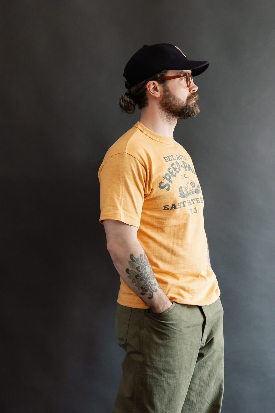 Warehouse & Co. orange slubby cotton T-shirt side view, front graphic, male model 5'9 165lbs athletic build