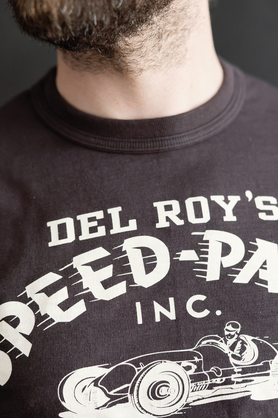 Close-up of slubby cotton graphic t-shirt front, male model, showing fabric texture and ribbed collar.