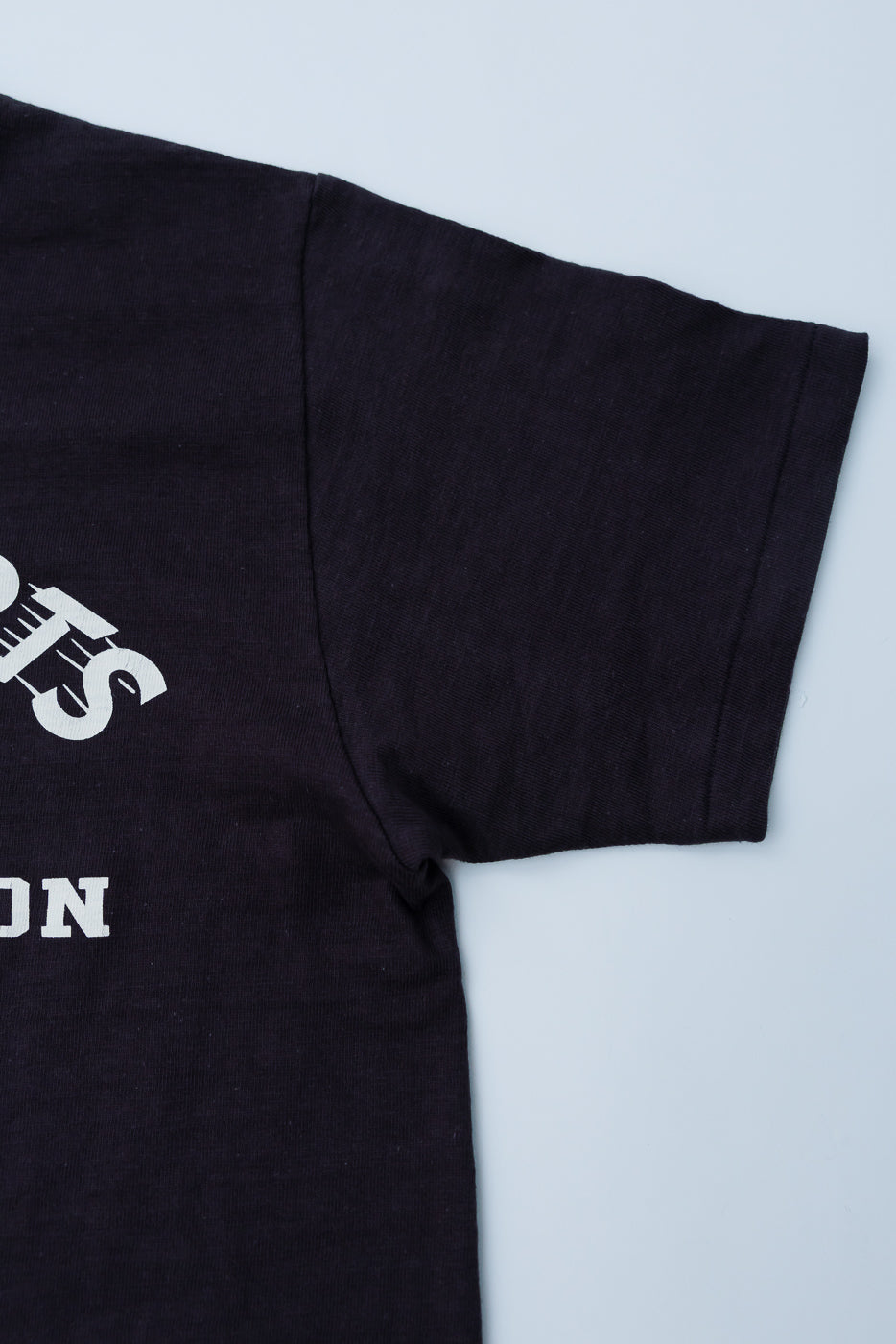 Close-up of Warehouse & Co. Lot 4601 black slubby cotton T-shirt, front left sleeve and chest text detail.