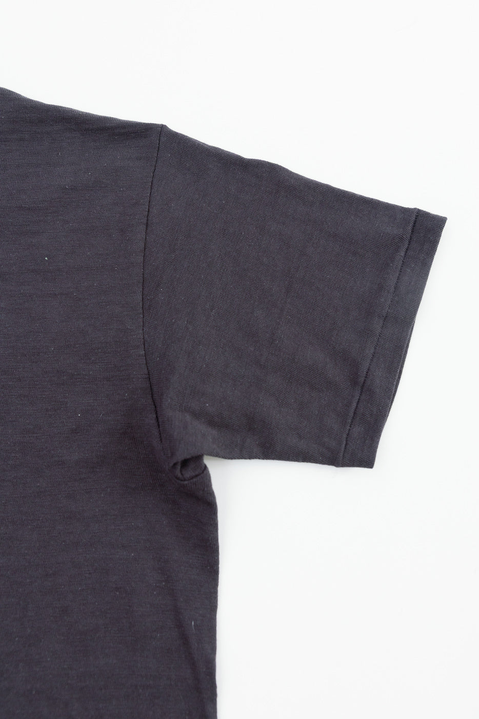 Close-up of slubby cotton T-shirt right sleeve, front side, showing fabric texture and hem.