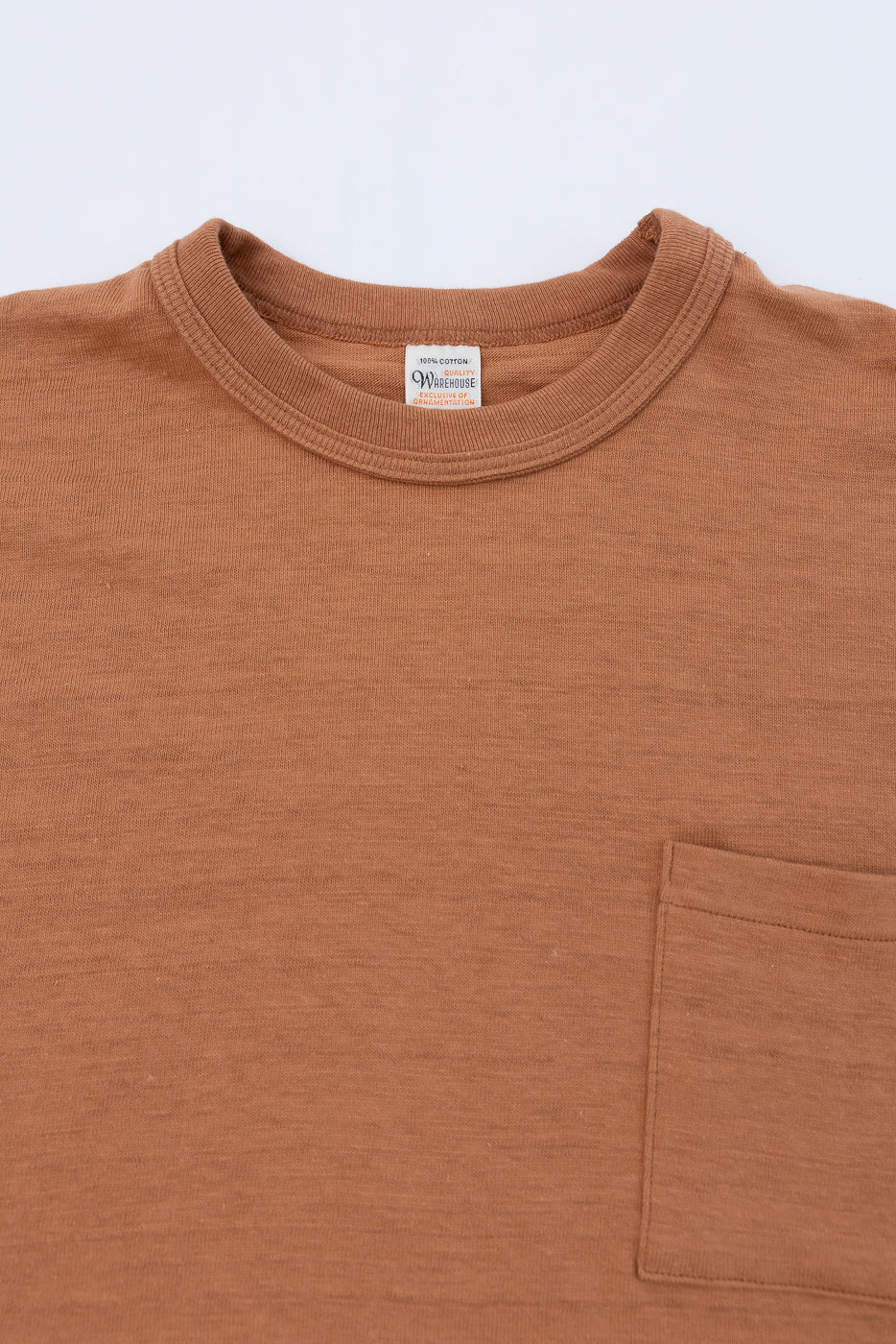 Close-up of the front neck and chest of a brown t-shirt showing the fabric and brand tag.