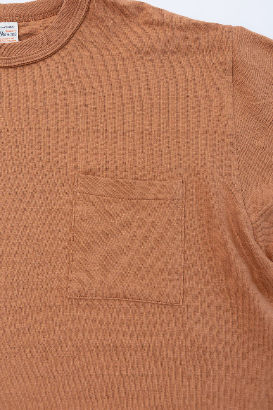 Close-up front view of a brown cotton t-shirt featuring a chest pocket and ribbed crewneck.