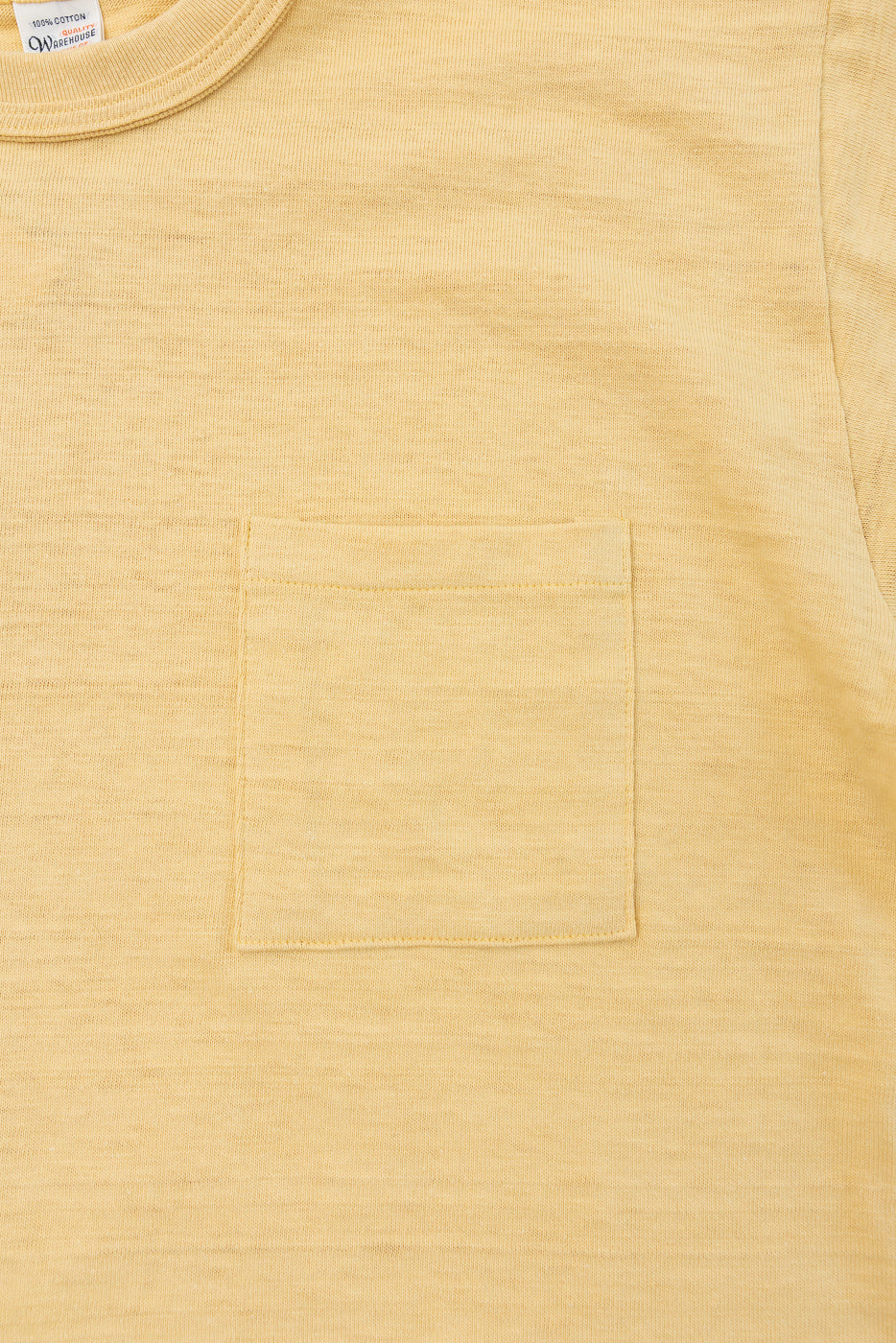 Close-up of the front of a yellow t-shirt showing fabric texture, pocket, and tag details.