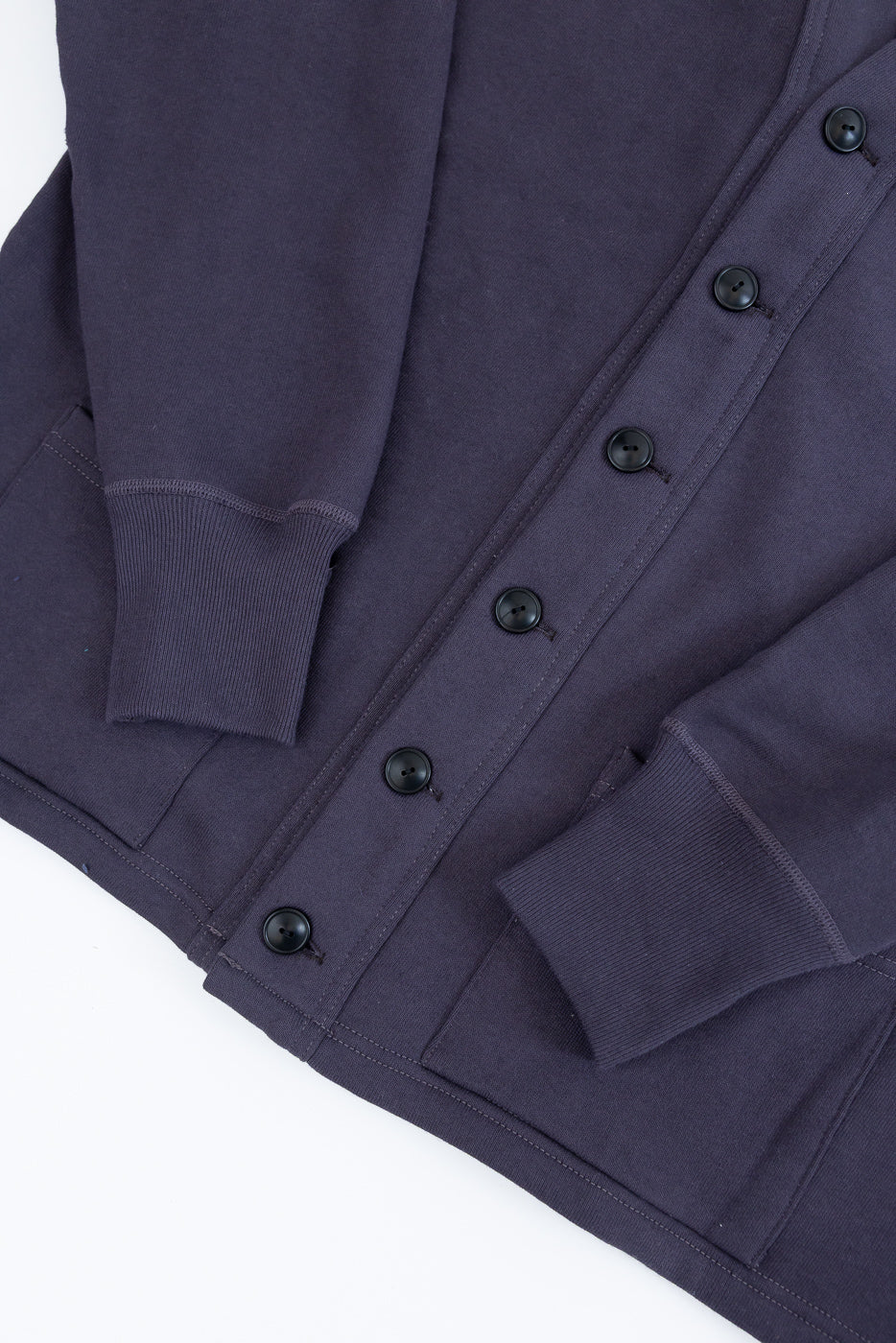 Close-up of front left side, dark navy 4-needle sweat cardigan with buttons, cuffs, and pockets visible.