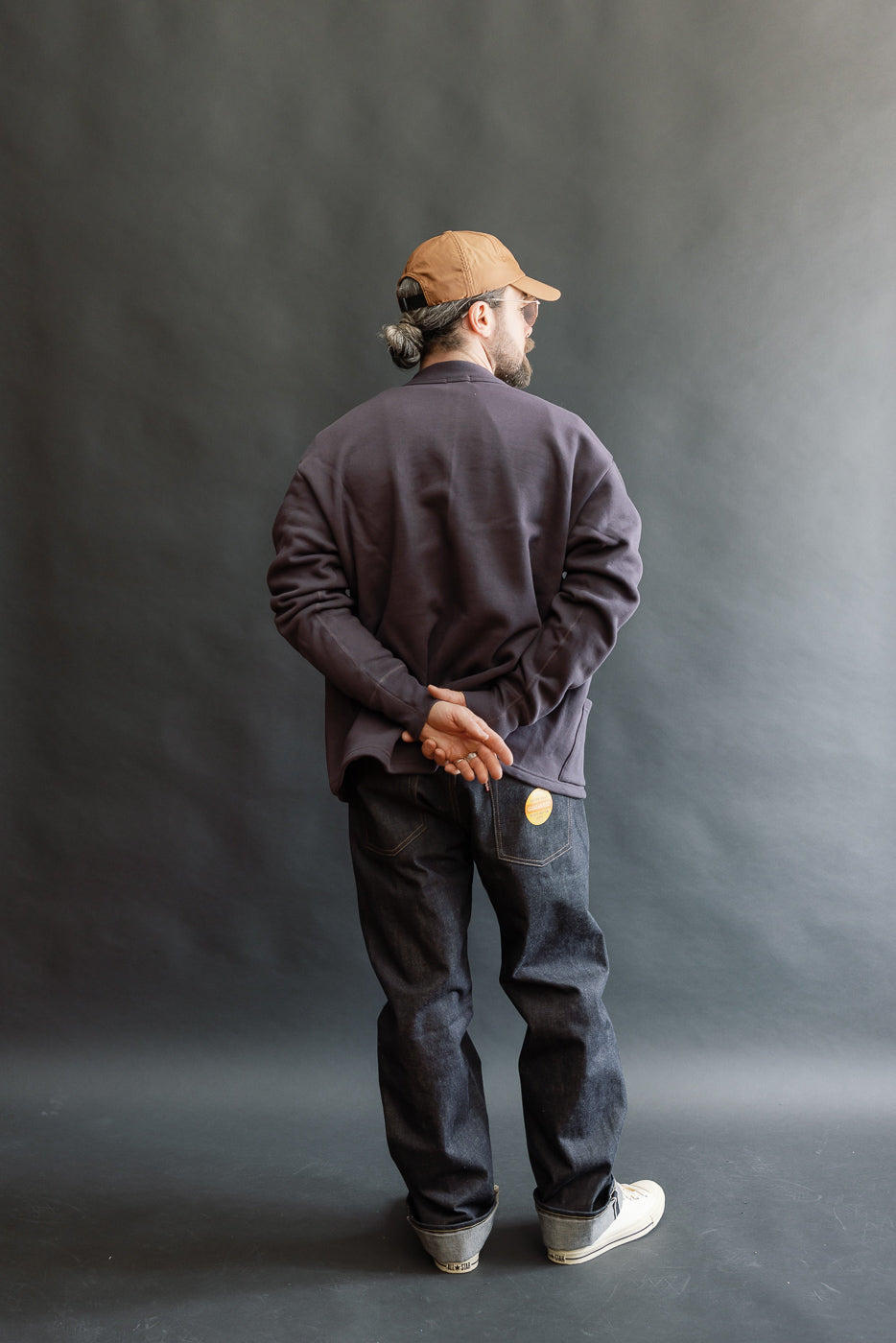 Full body back view of male model 5'9 165lbs athletic build wearing dark navy sweat cardigan and jeans.