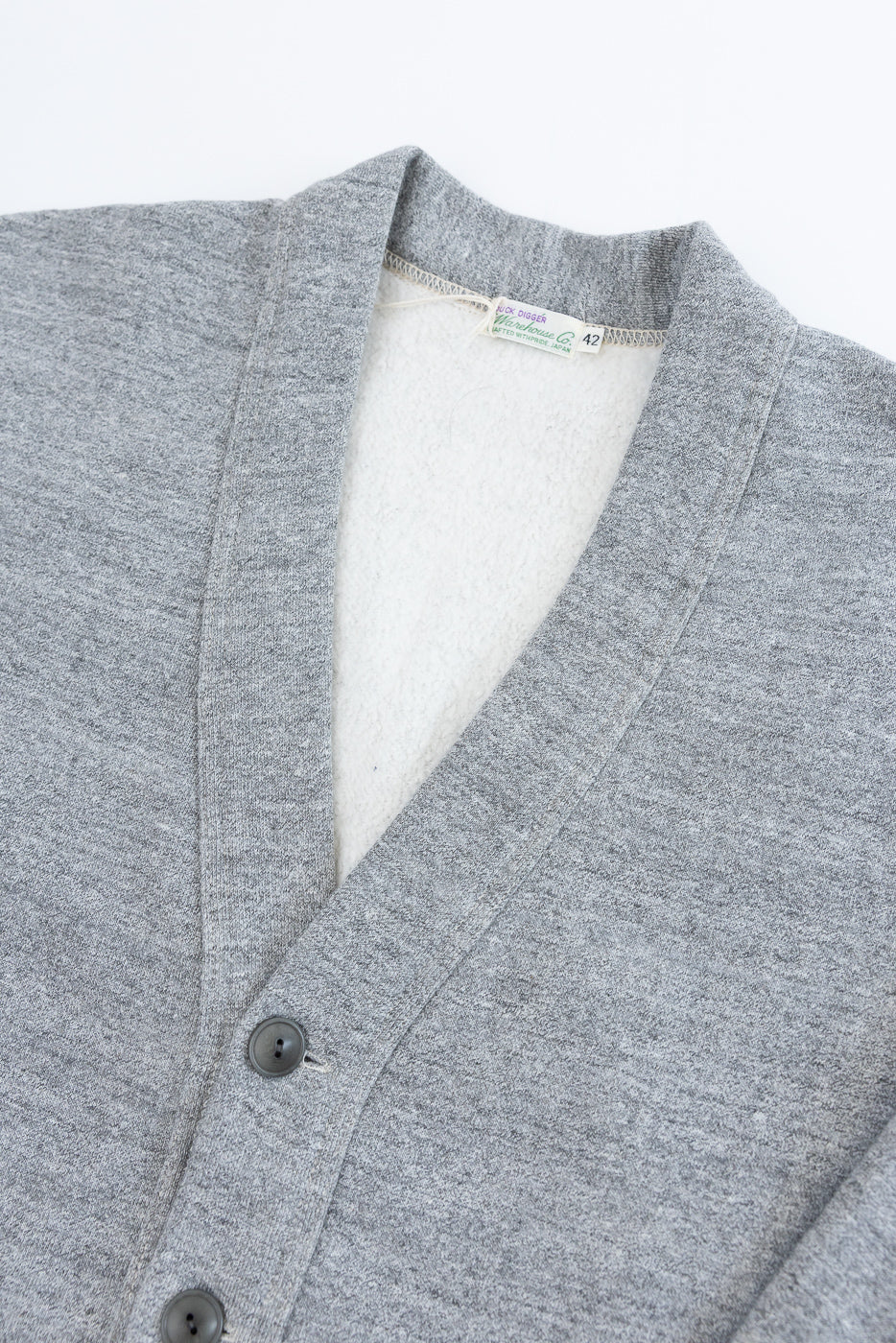 Close-up of front upper section, heather grey cardigan, showing buttons, fabric texture, collar, and inner tag.