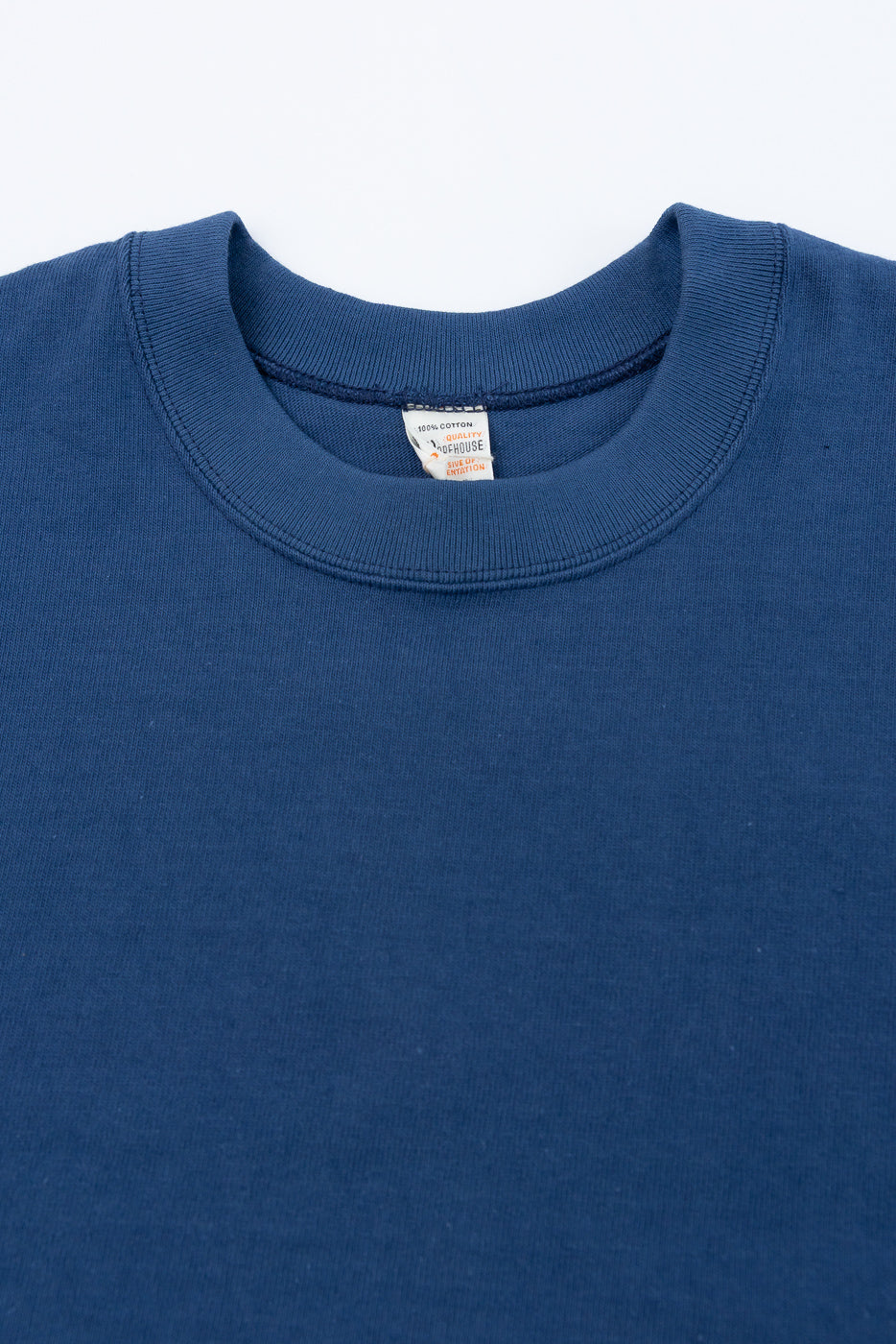 Close-up front view of a blue cotton crewneck sweatshirt collar and interior tag detail.