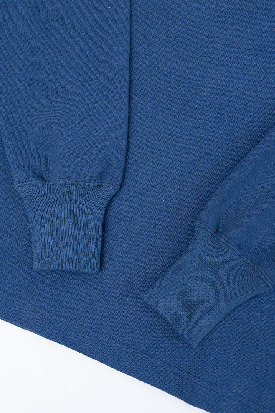 Close-up of blue sweatshirt ribbed cuffs and sleeve fabric texture.
