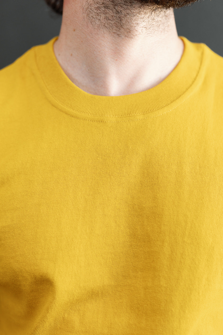 Close-up front view of a yellow crewneck shirt collar on a 5'9