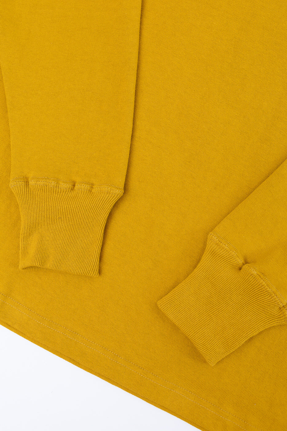 Close-up of the ribbed cuffs and fabric texture on the sleeves of a mustard yellow long-sleeve shirt.