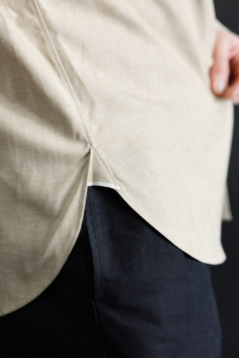Close-up of male model side hem on oxford shirt, showcasing curved hem split detail.