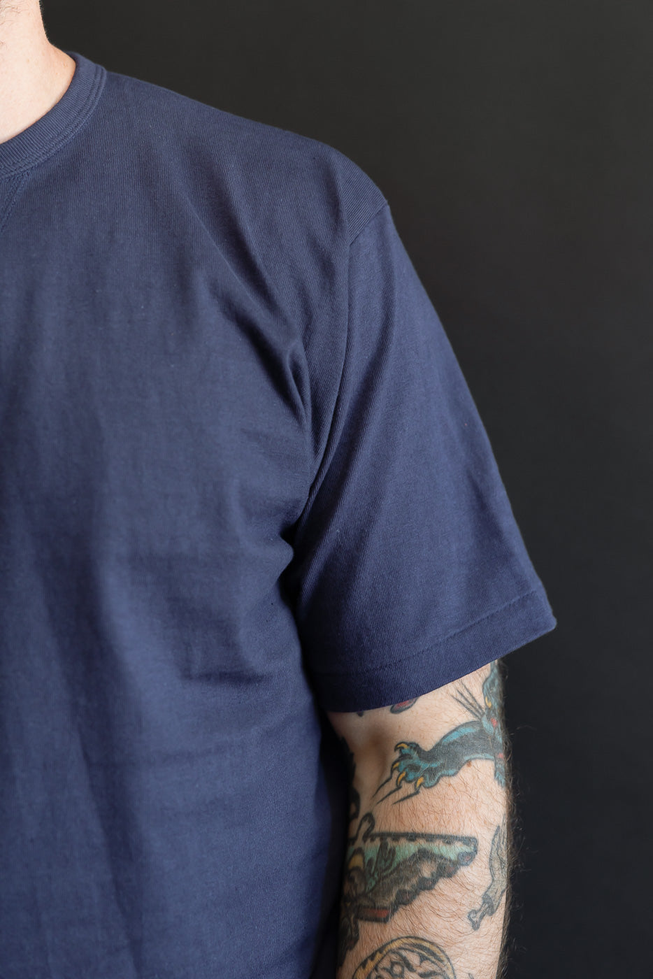 Close-up side view of a navy blue crewneck t-shirt on a male model, 5'9