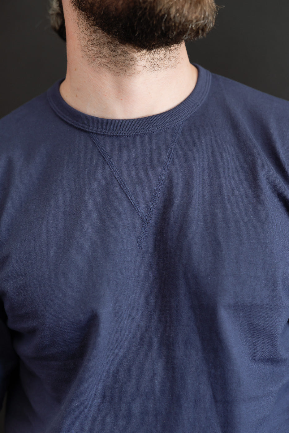 Close-up front view of a navy blue crewneck sweatshirt on a male model, 5'9