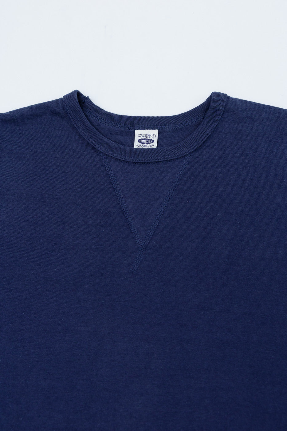 Close-up of the front neckline of a navy blue sweatshirt showing the crew collar and brand tag.