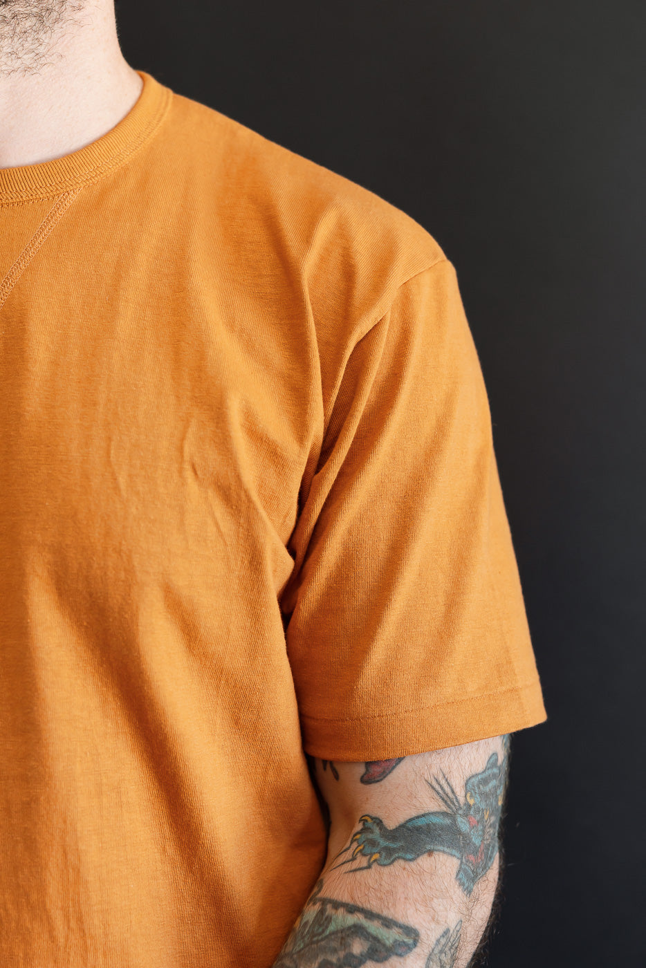 Close-up, right side of an ochre t-shirt on a male model, 5'9