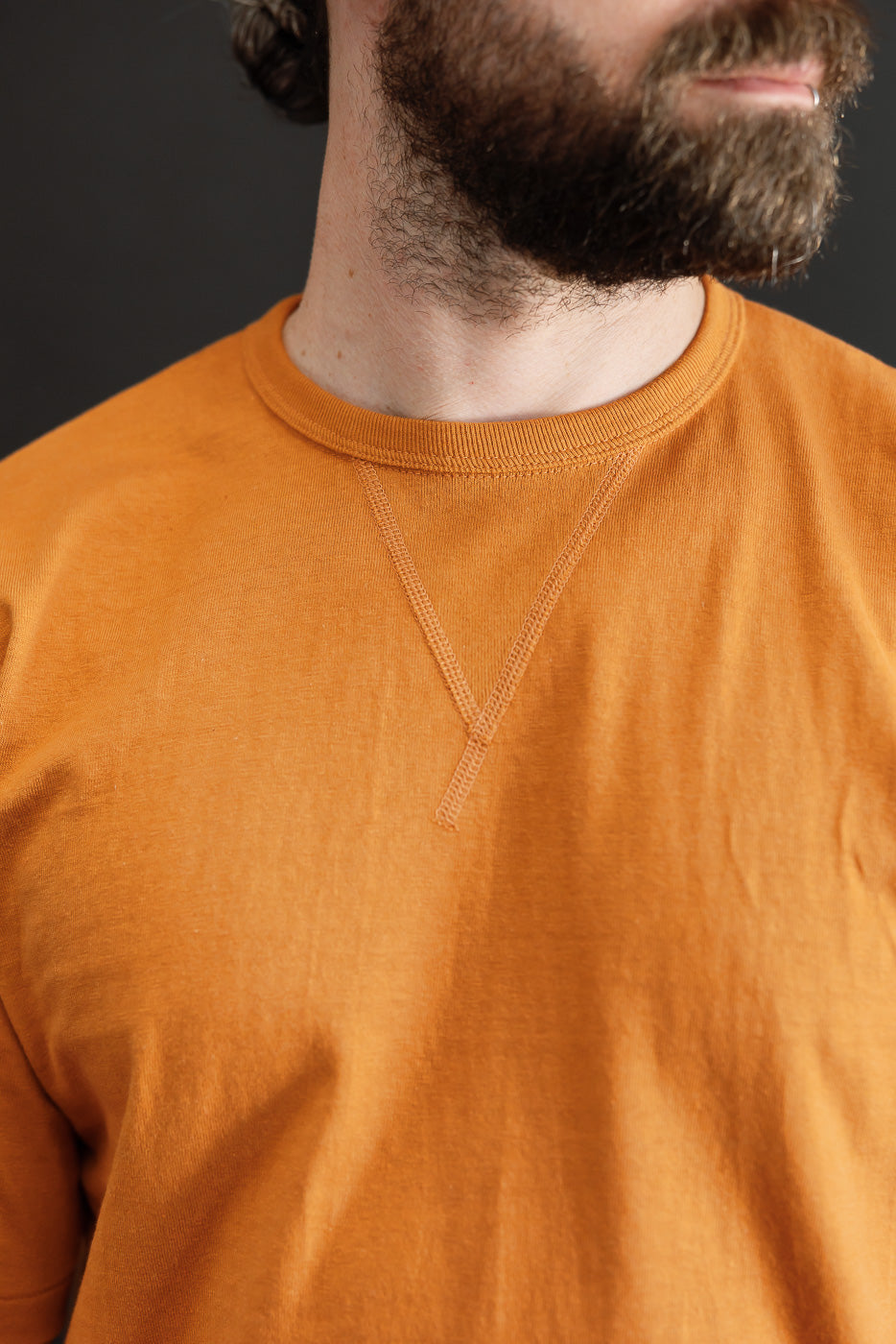 Close-up front view of an orange t-shirt crew neck on a 5'9