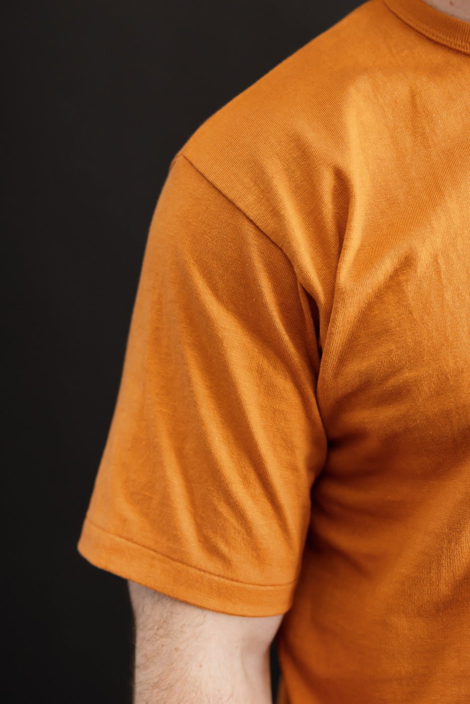 Close-up side view of an orange t-shirt on a male model, 5'9
