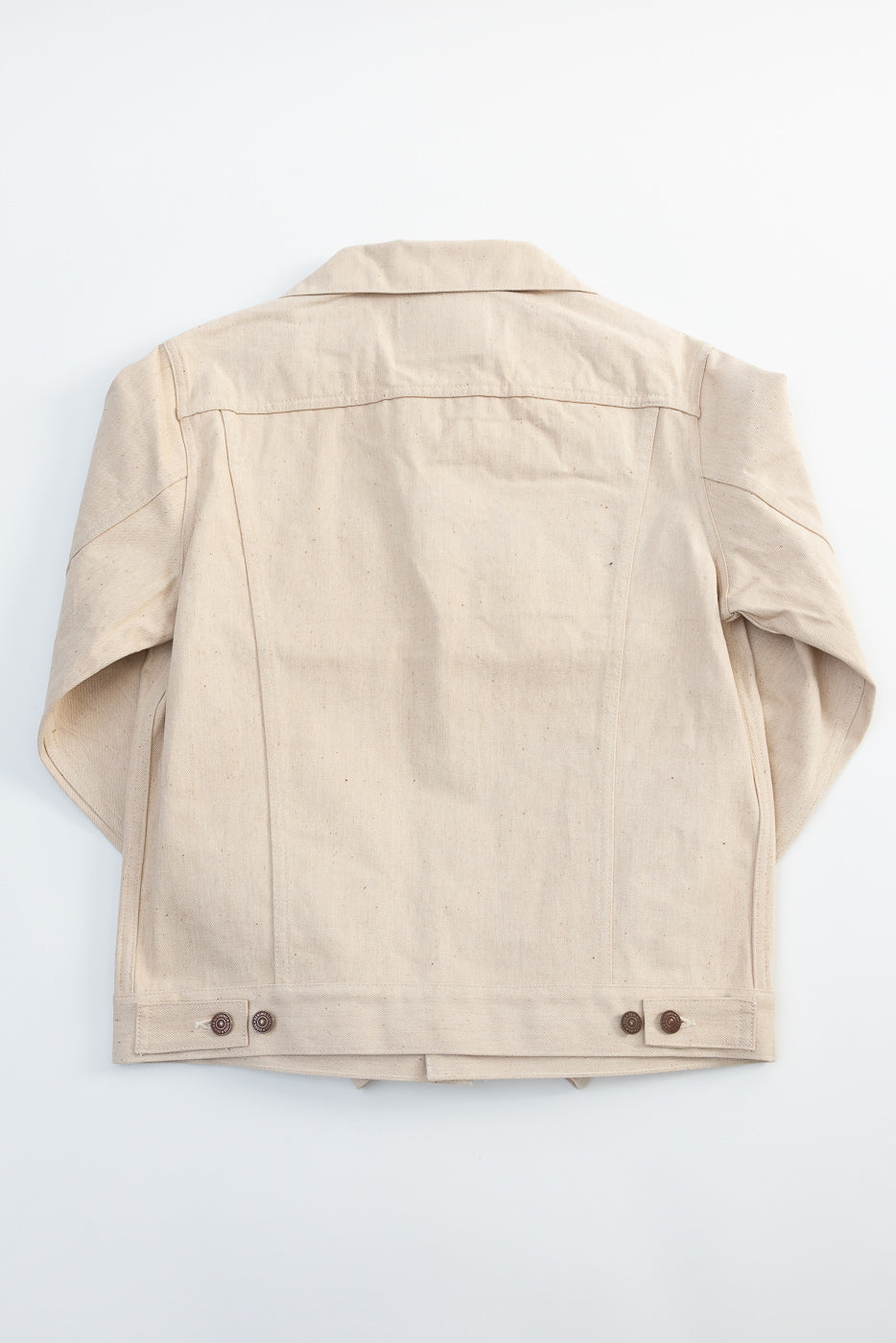 Back view flat lay of Warehouse Denime Lot 66M ecru cotton denim jacket, showing back panel, seams, and hem adjuster buttons.