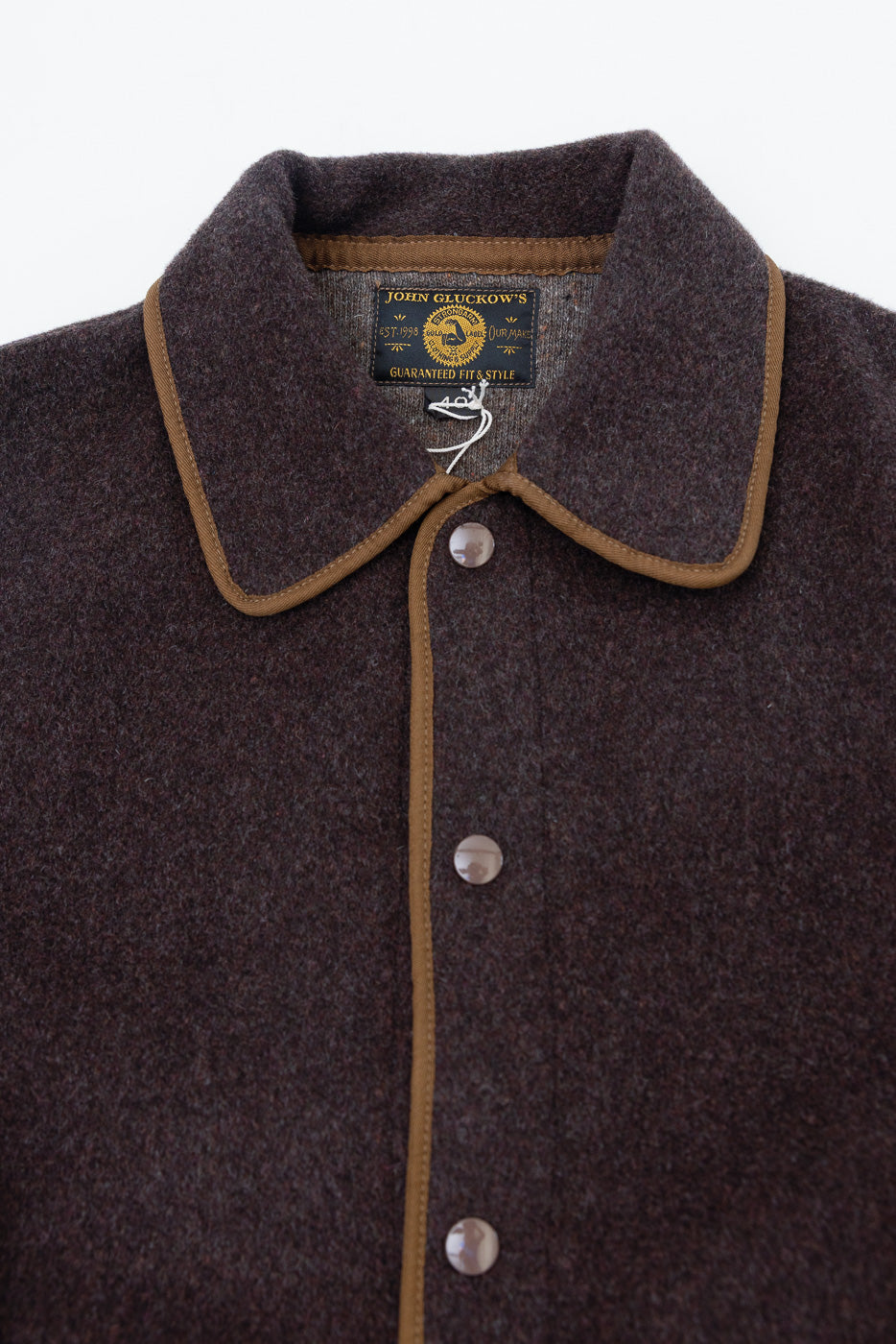 Close-up front view of brown wool jacket collar, buttons, and fabric texture.