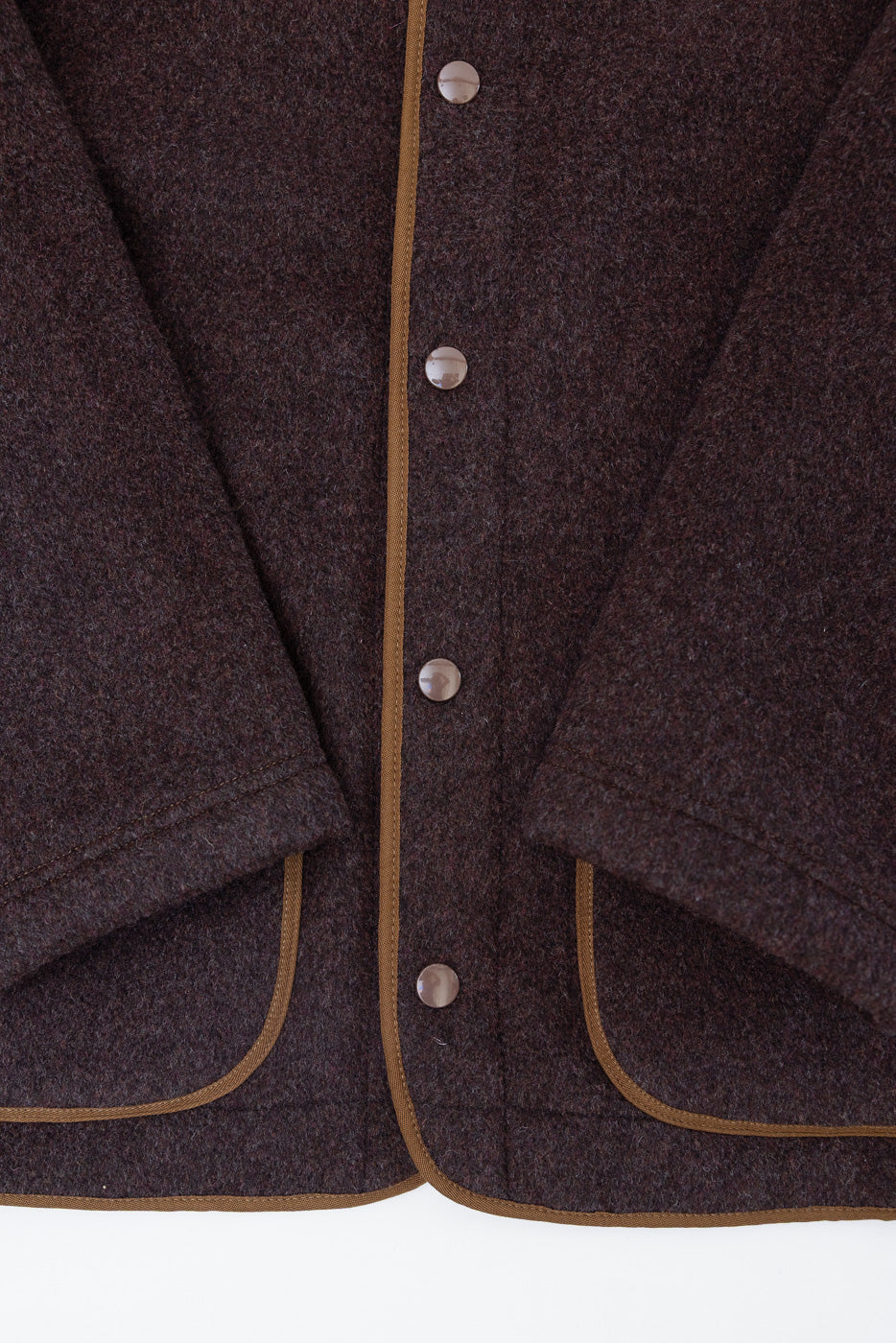 Close-up front view of dark brown wool jacket showing button details and tan piping edges.