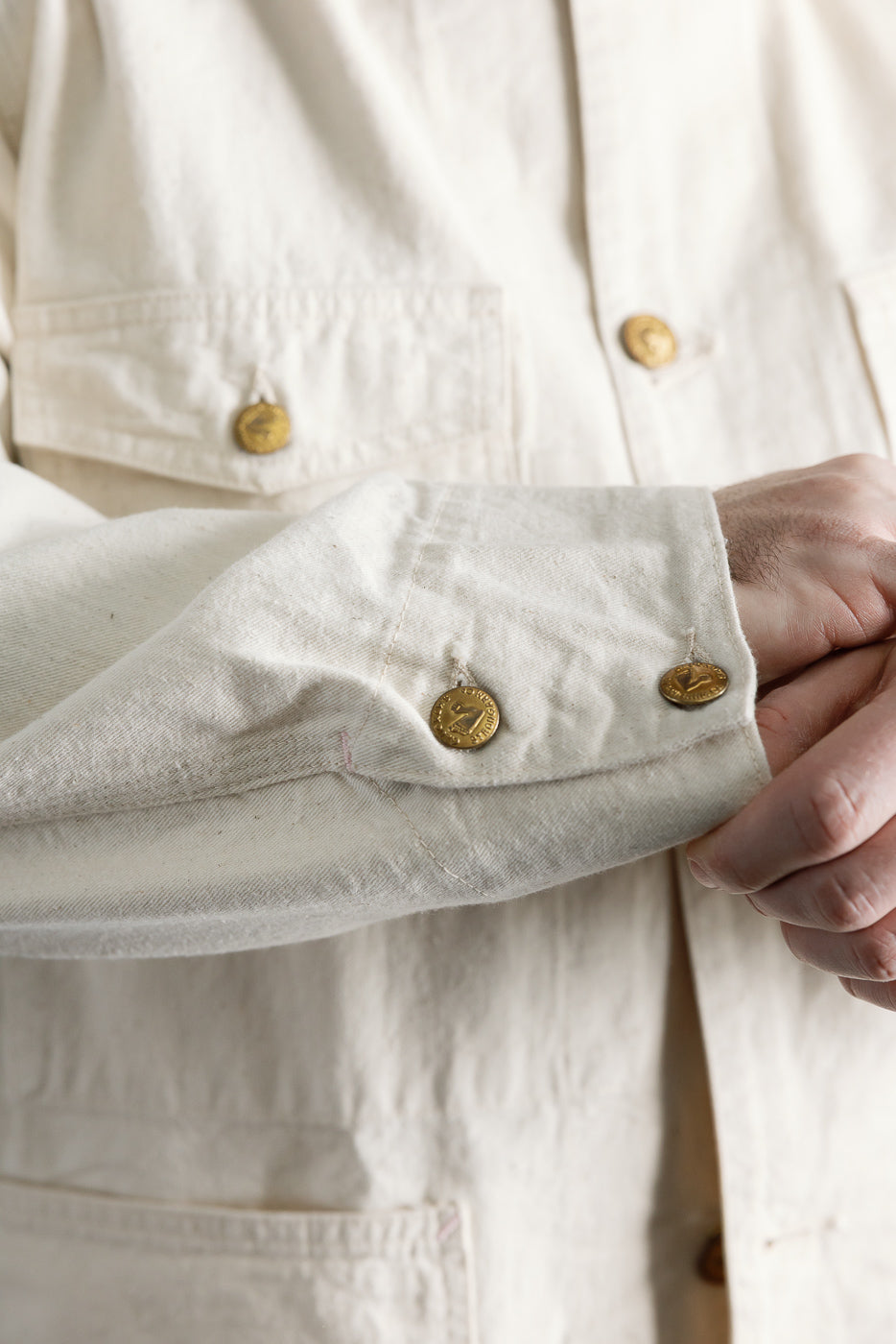 Close-up of front left sleeve and chest of ecru house painter's jacket on male model, 5'9