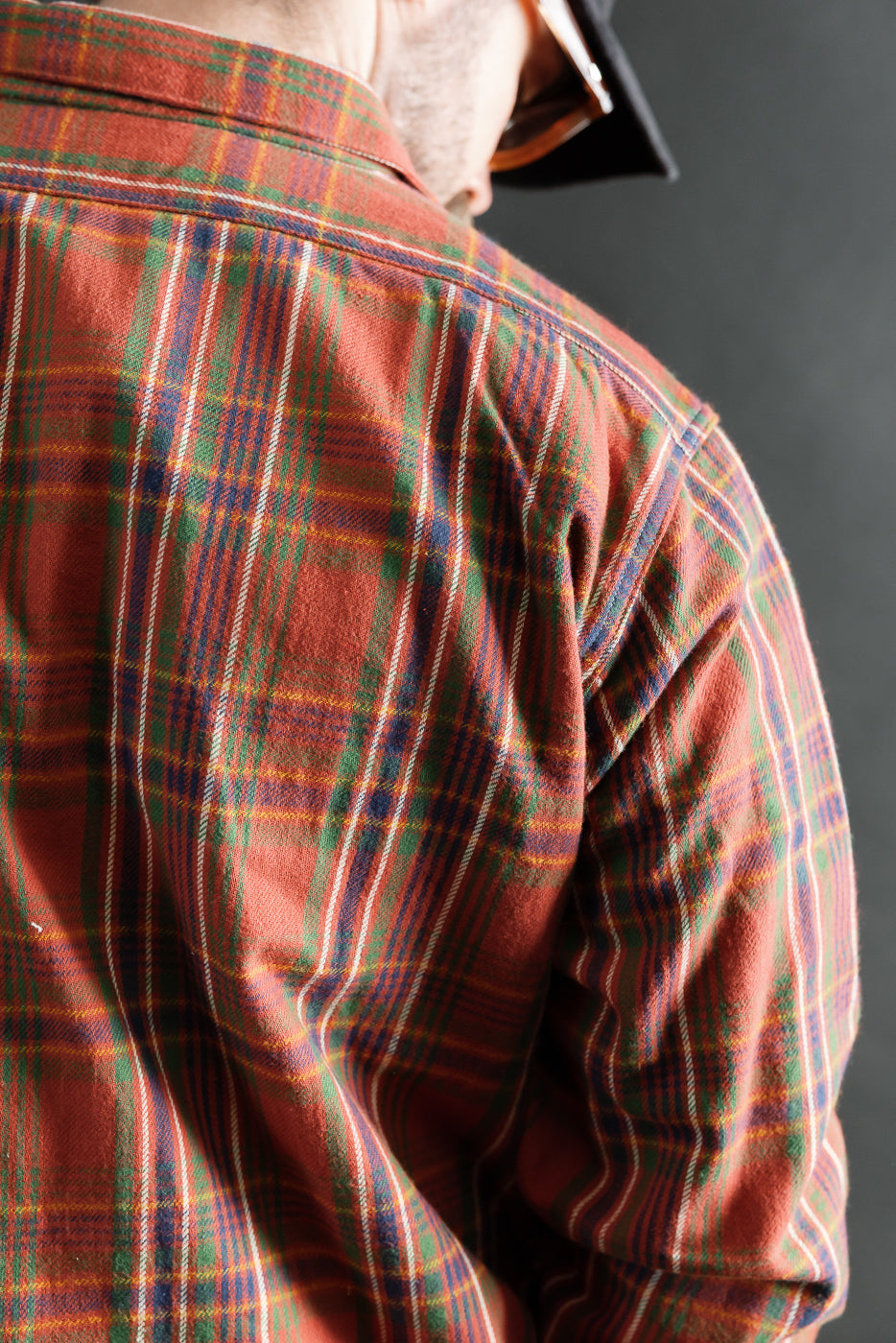 Close-up back view of red plaid flannel shirt on male model, highlighting fabric texture