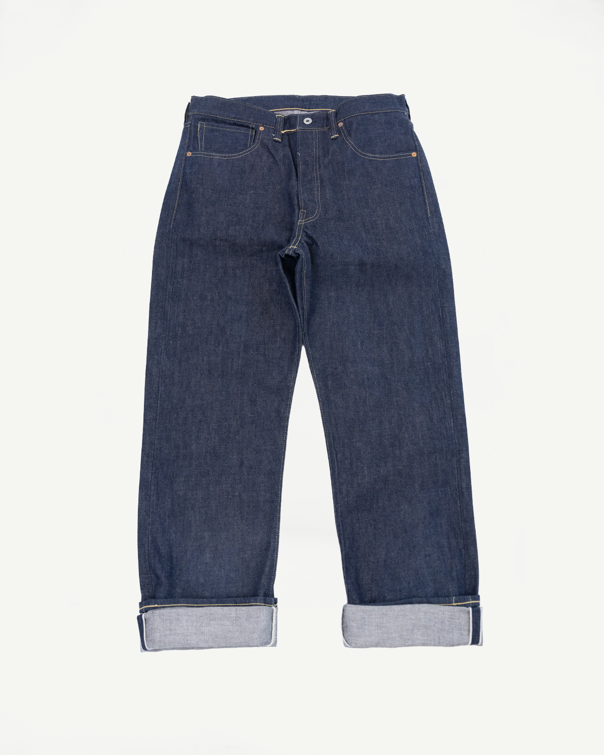 Front view flat lay of dark indigo selvedge denim jeans with cuffed hems.