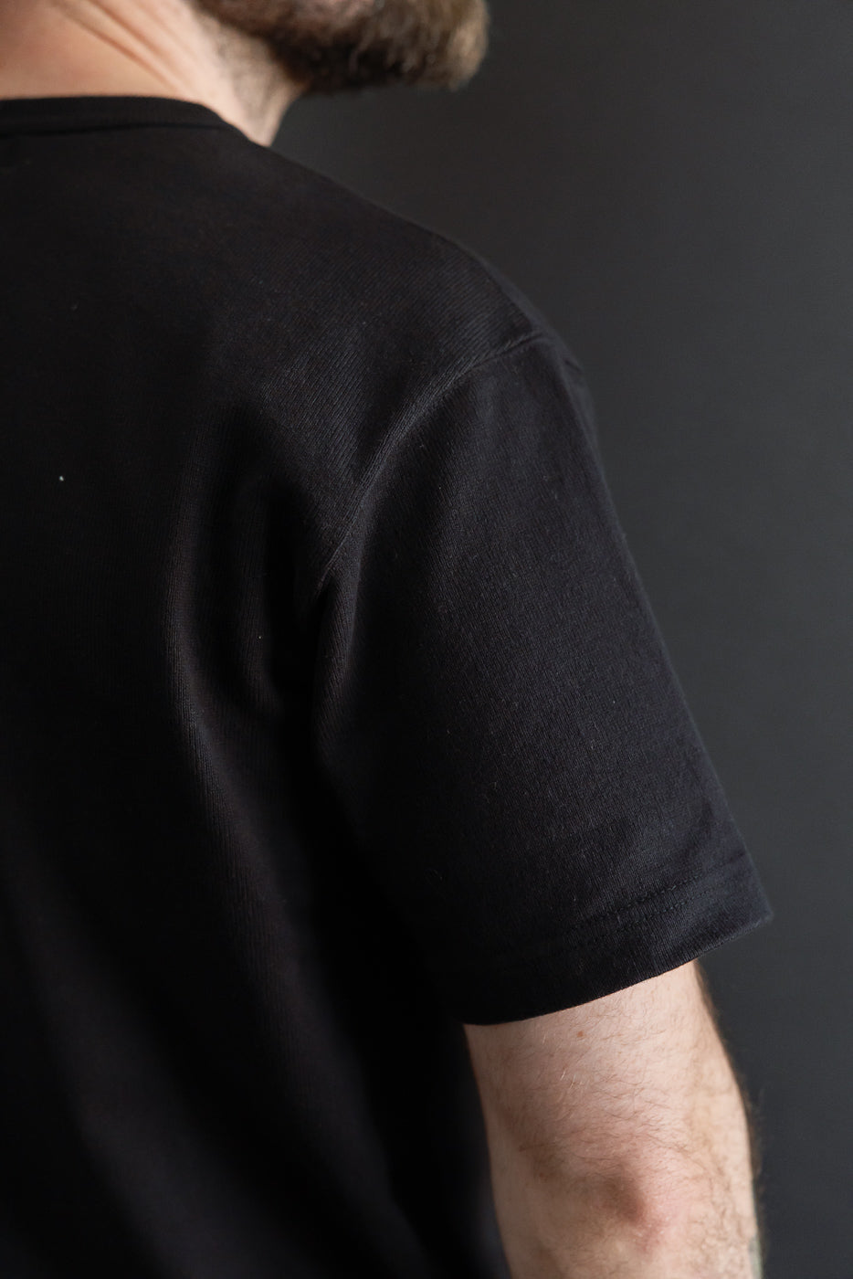 Close-up back view of a black t-shirt on a male model, 5'9