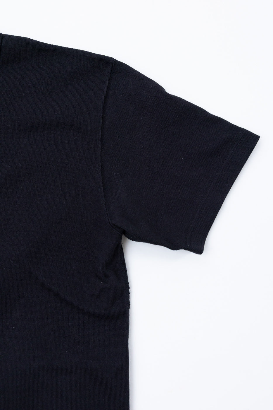 Close-up of the right sleeve and side of a black cotton t-shirt flat lay.