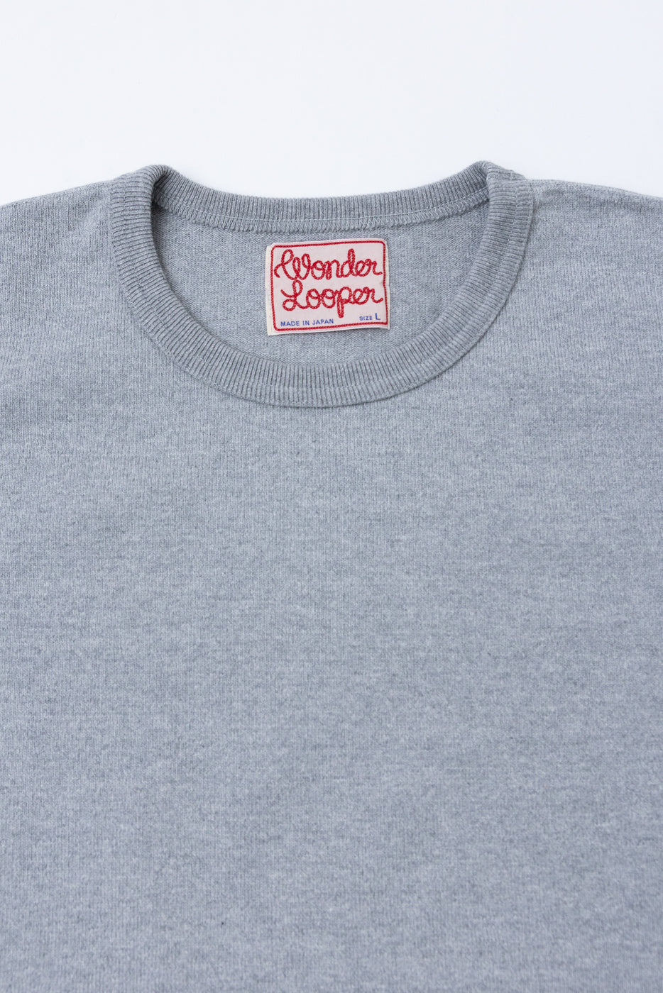 Close-up of the front neckline of a grey sweater showing the Wonder Looper brand tag.