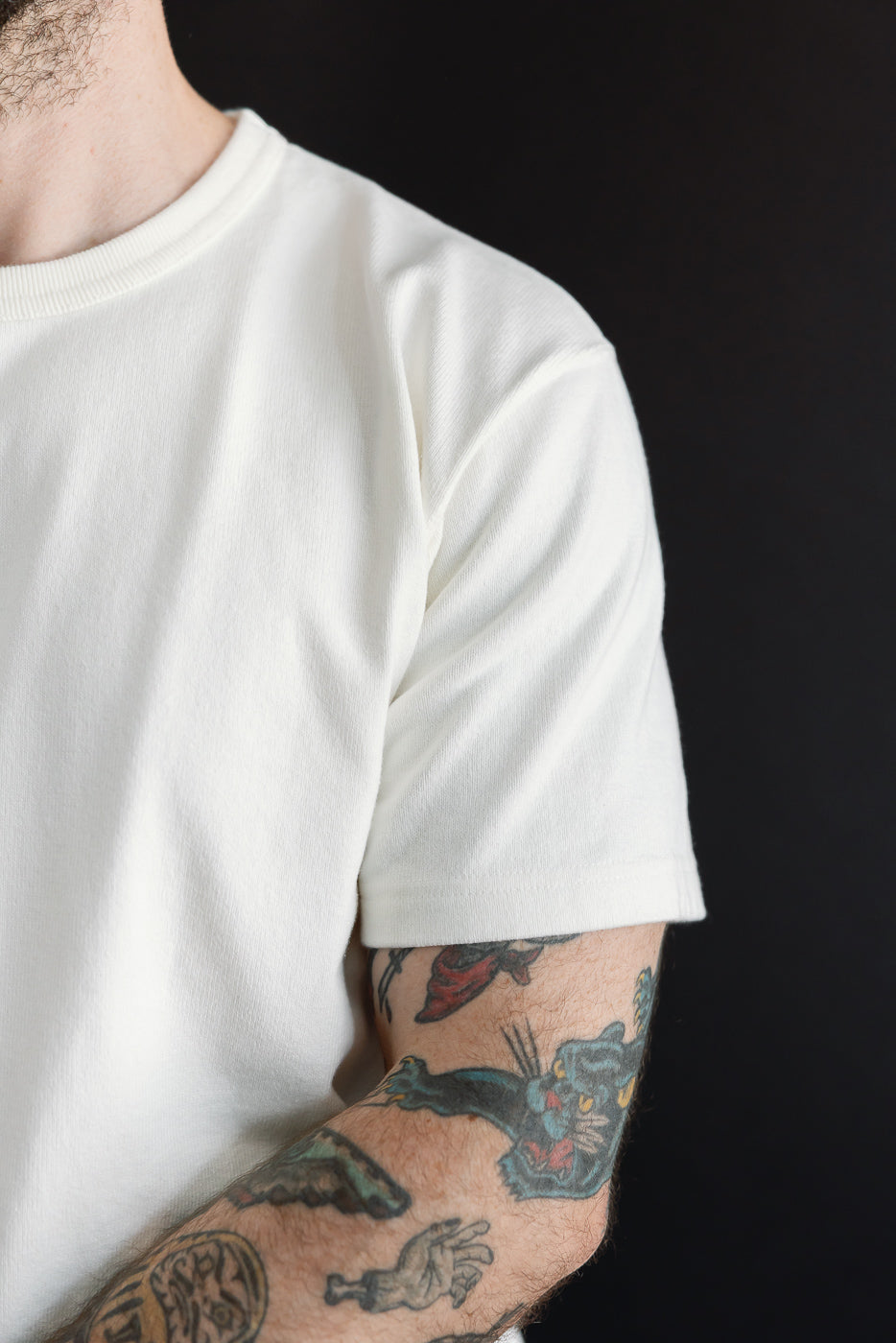 Close-up side view of a white t-shirt crew neck and sleeve on a 5'9