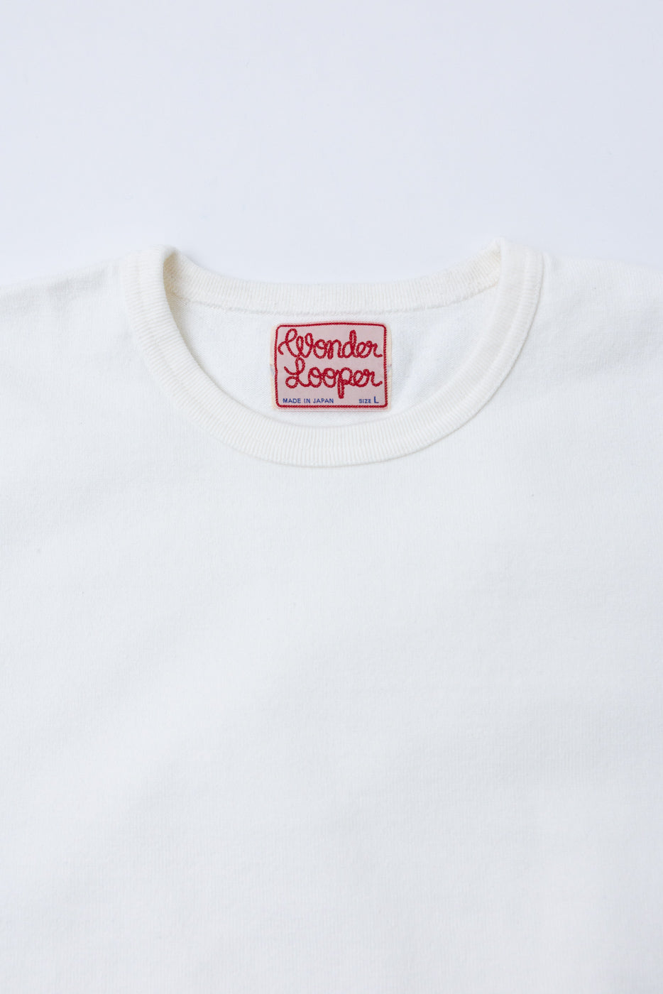 Close-up of the inner back neckline of a white t-shirt featuring a red Wonder Looper tag.