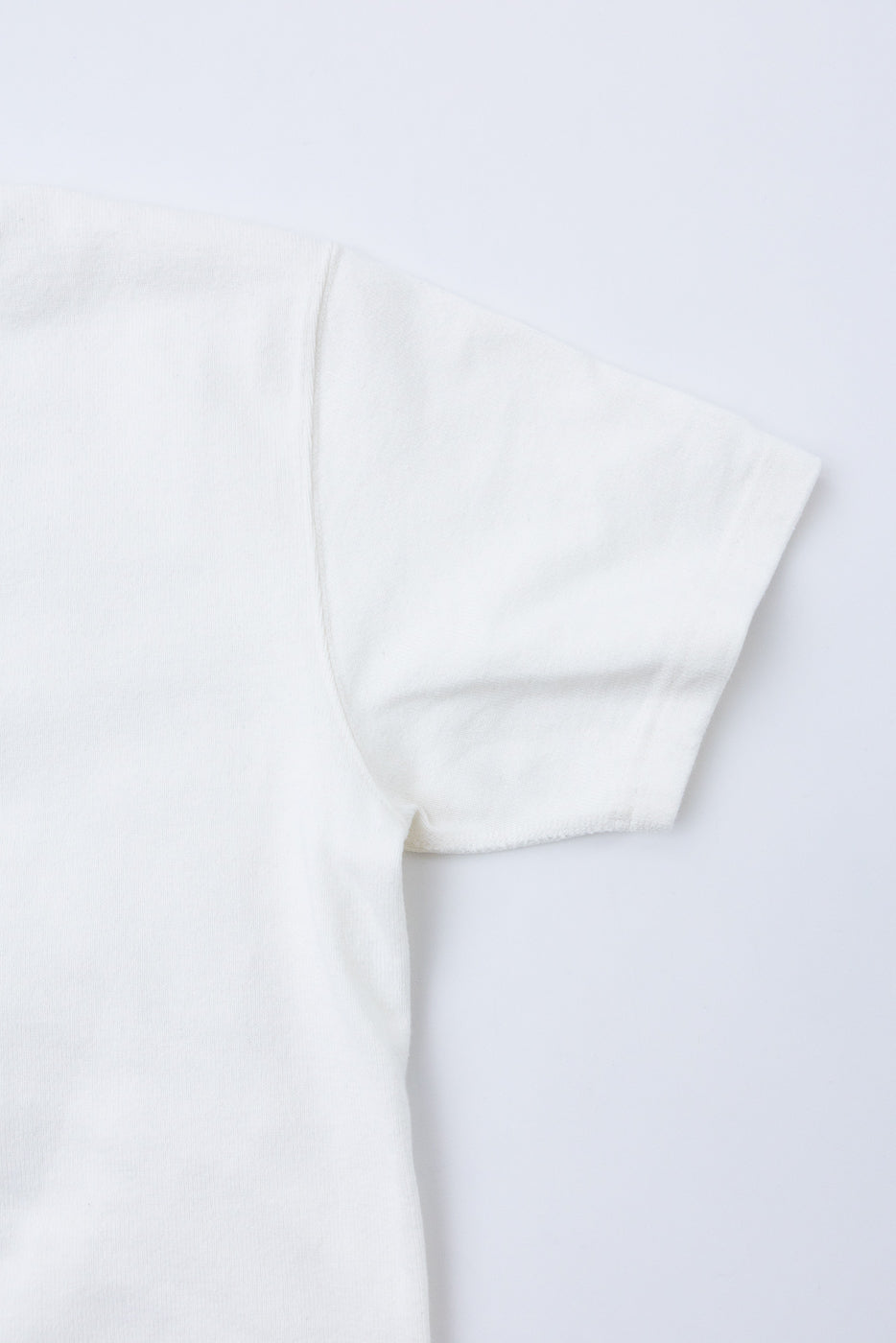 Close-up of the right sleeve and shoulder area of a white cotton t-shirt flat lay.