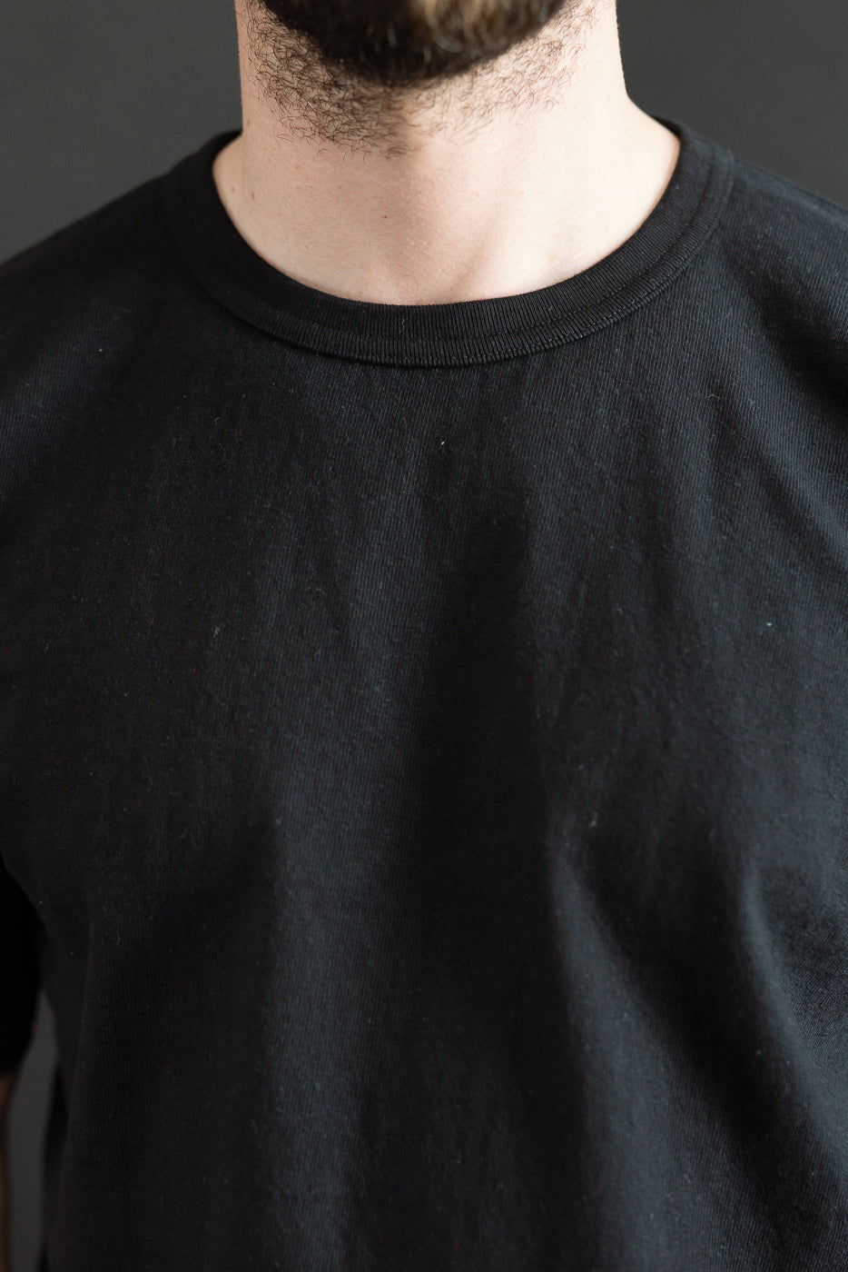 Close-up of a person wearing the ELS Recycled Cotton Slub Crewneck T-Shirt - Black, highlighting its refined texture and modern athletic fit, exemplifying Dant's commitment to premium Japanese-made apparel.