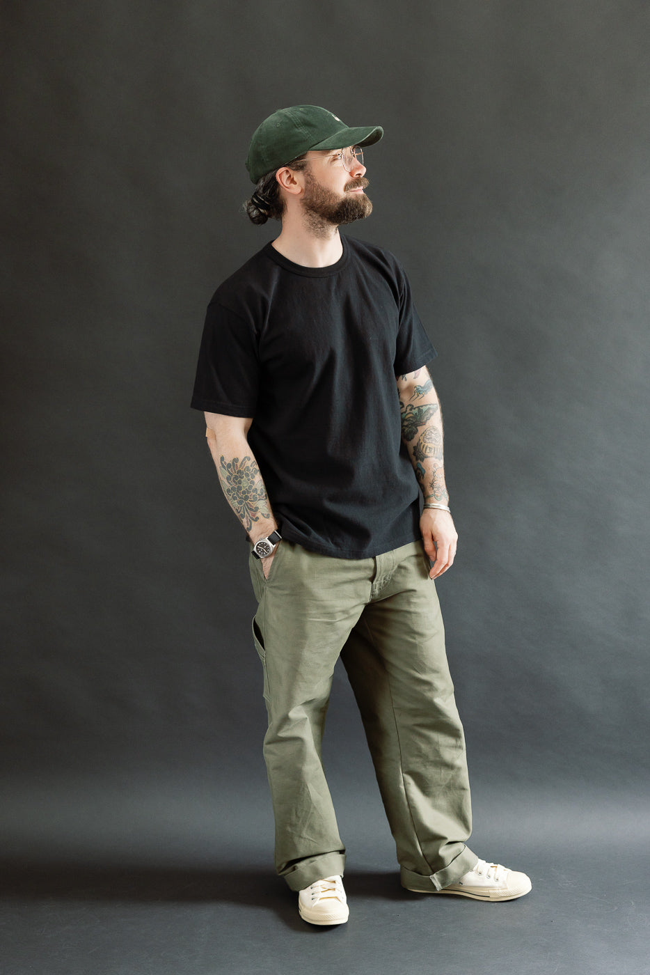 A bearded man models the ELS Recycled Cotton Slub Crewneck T-Shirt - Black, showcasing its modern athletic fit and premium texture against a dark-gray backdrop.