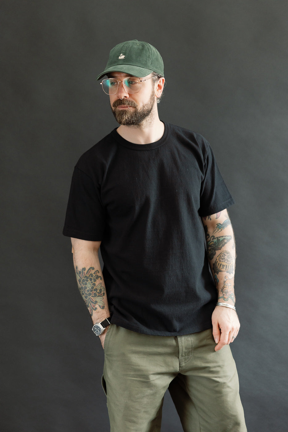 Man in a black ELS Recycled Cotton Slub Crewneck T-Shirt, showcasing its athletic fit and textured fabric, paired with olive-green pants, embodying Dant's premium menswear style.