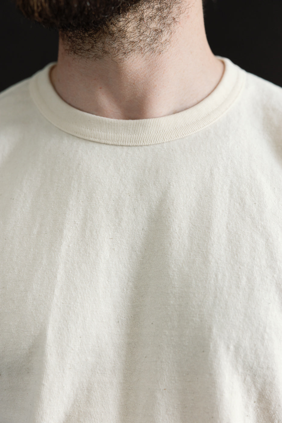 Model wearing ELS Recycled Cotton Slub Crewneck T-Shirt - Ecru, showcasing its modern athletic fit and ribbed collar, capturing the garment's premium Japanese craftsmanship and textured fabric.