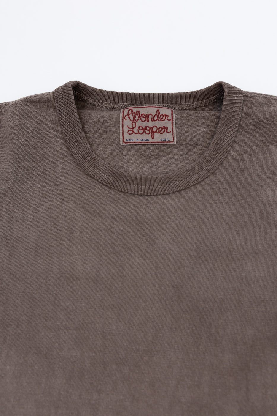 Close-up front view of brown t-shirt collar with Wonder Looper tag, ribbed neckline, and fabric texture detail