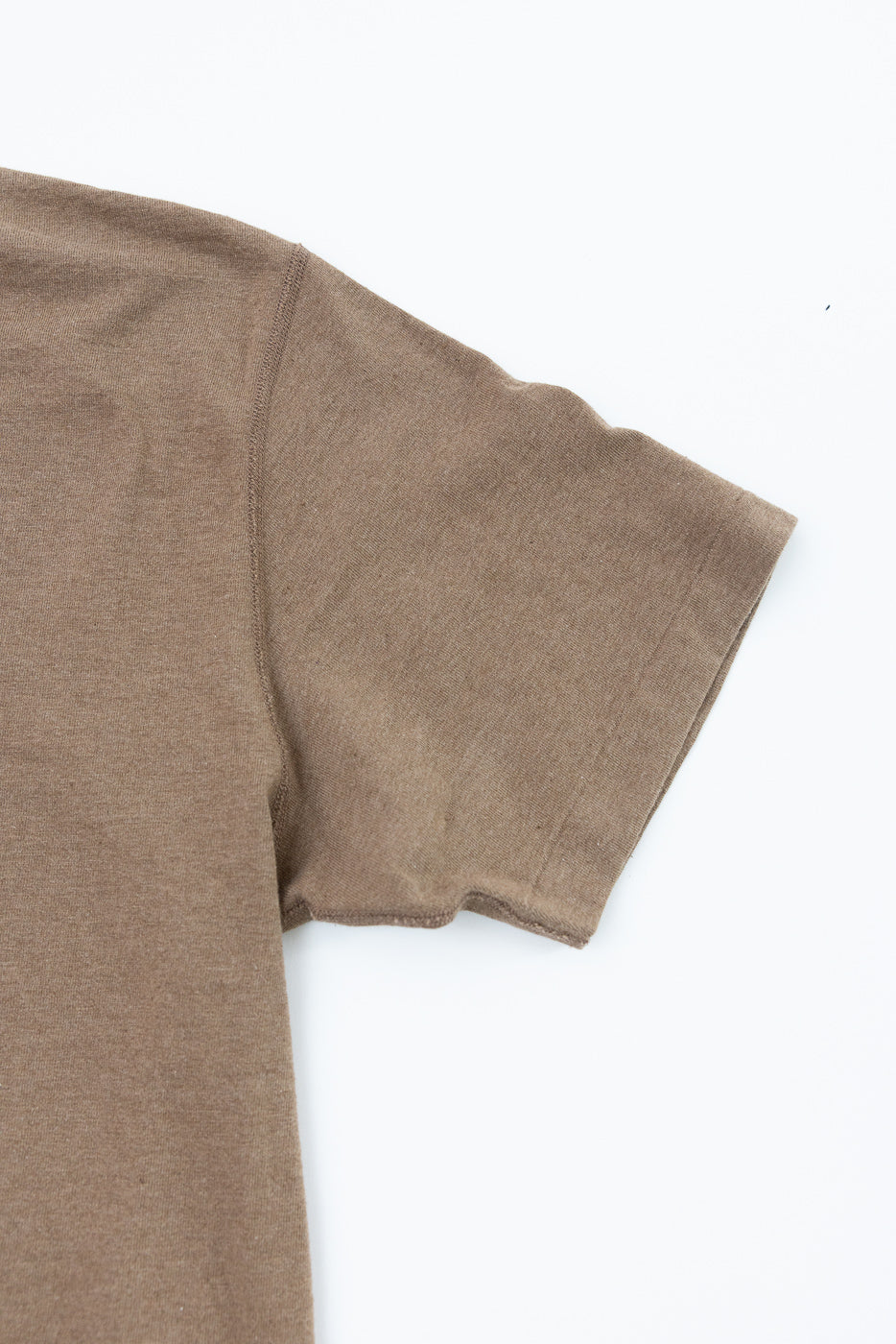 Close-up front view of brown short-sleeve tee showing shoulder seam and ribbed sleeve hem texture