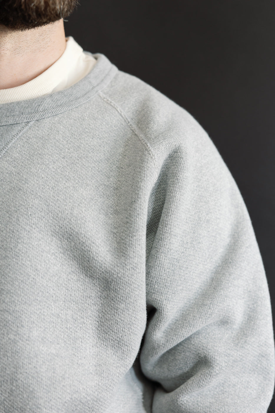 Close-up of grey crewneck sweatshirt fabric and shoulder on male model, 5'9