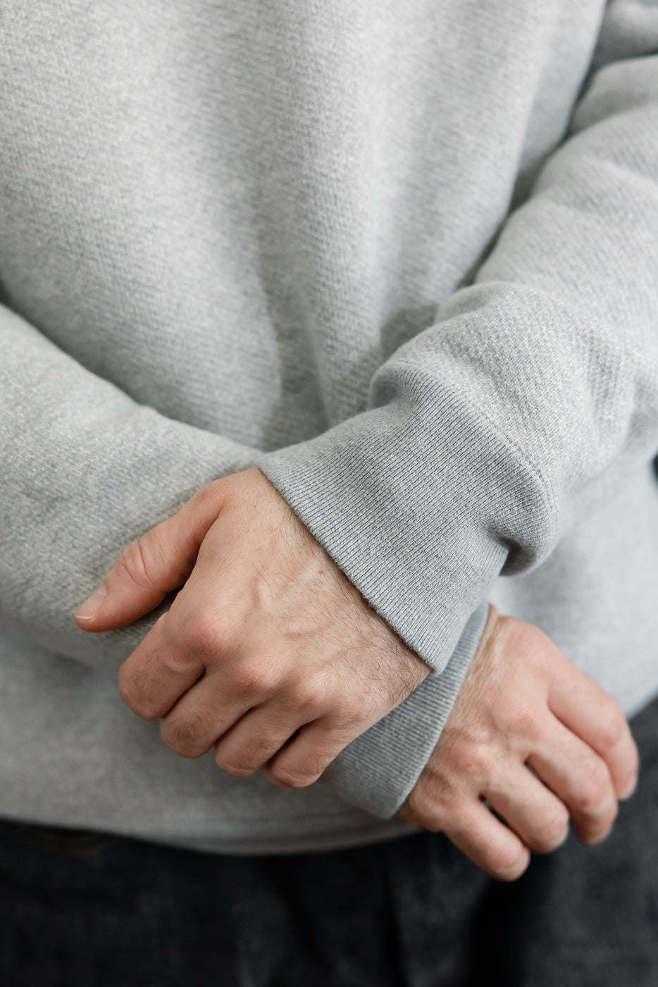 Close-up of the ribbed cuff and sleeve texture on a light grey sweatshirt.