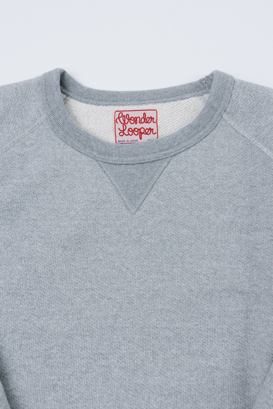 Close-up of the front neckline of a grey Wonder Looper sweatshirt showing the ribbed collar and brand tag.