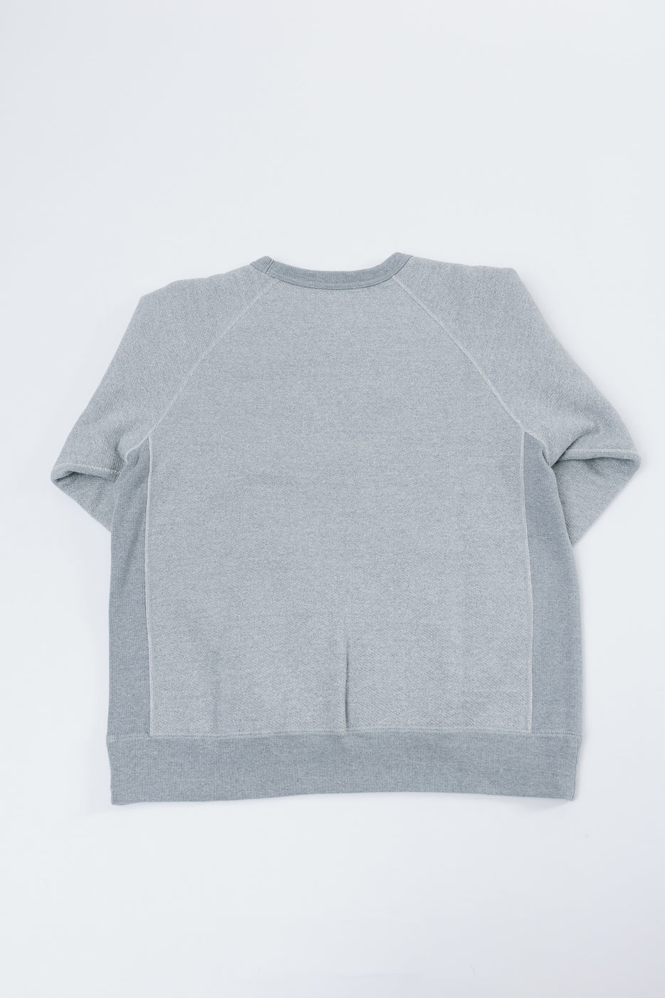 Back view flat lay of a grey heathered raglan sleeve sweatshirt showing the rear hem and neckline.