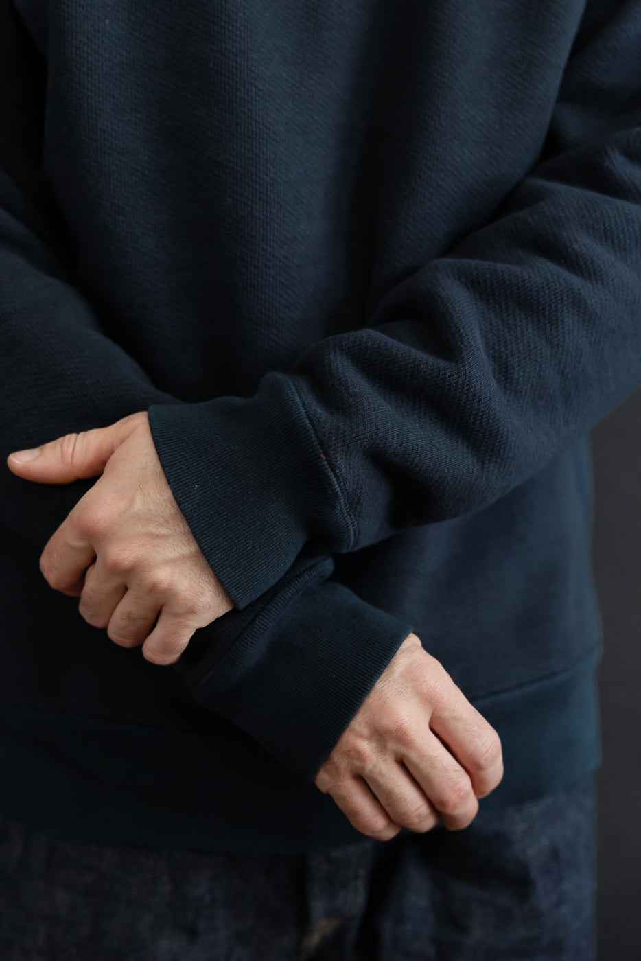 Close-up of navy sweatshirt sleeve and cuff on a male model, 5'9