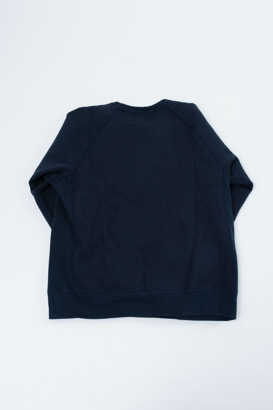 Back view flat lay of a navy blue crewneck sweatshirt with raglan sleeves.