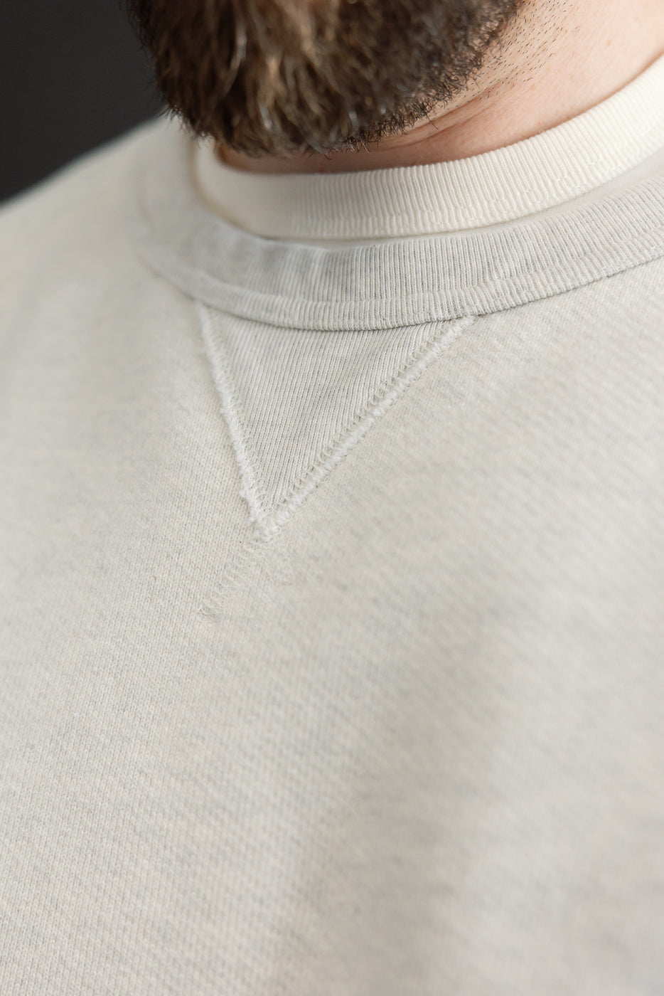 Close-up front view of a white crewneck collar on a male model, 5'9
